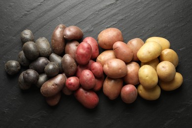 Photo of Different types of potatoes on black table, flat lay