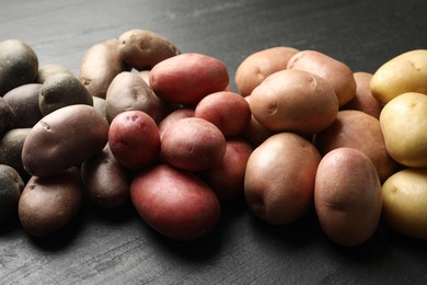 Photo of Different types of potatoes on black table, closeup