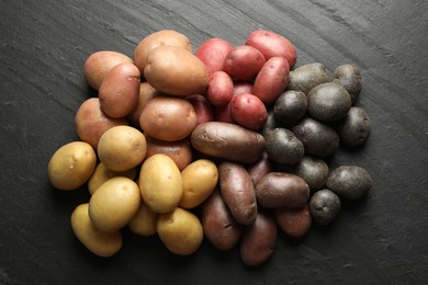 Photo of Different types of potatoes on black table, flat lay