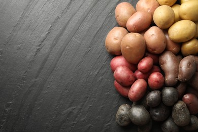 Photo of Different types of potatoes on black table, flat lay. Space for text