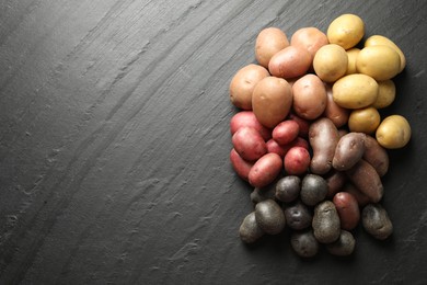 Photo of Different types of potatoes on black table, flat lay. Space for text