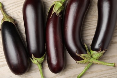Photo of Many ripe eggplants on light wooden table, flat lay