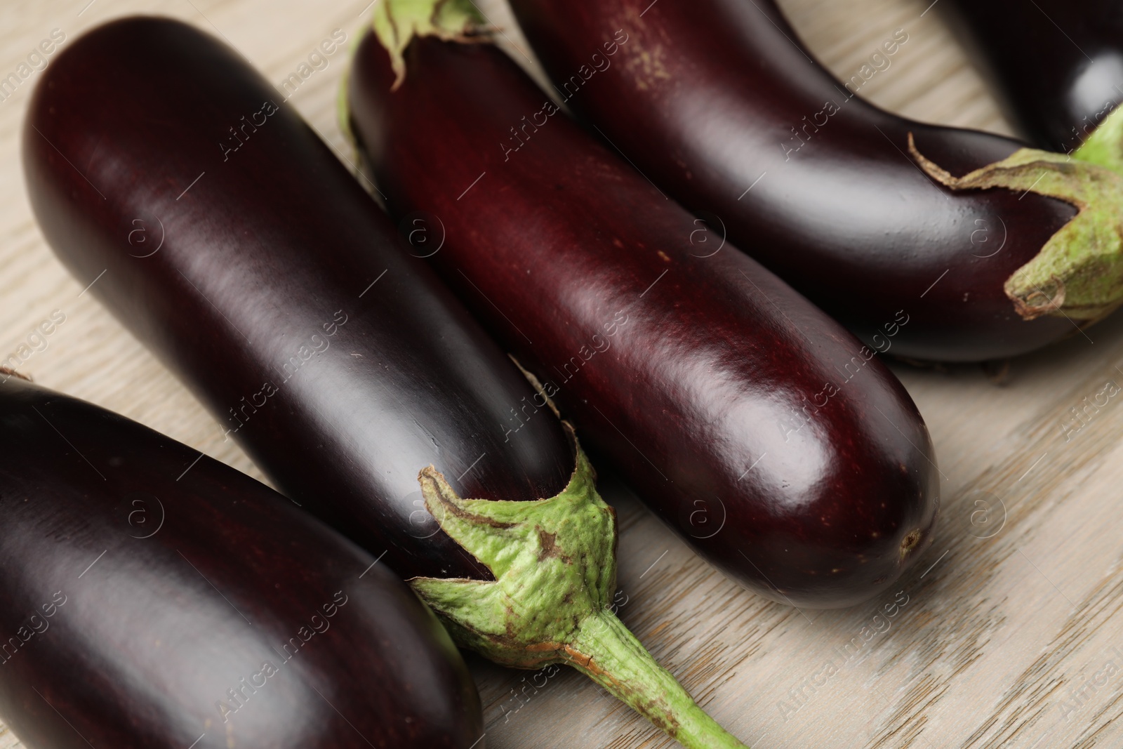 Photo of Many ripe eggplants on light wooden table, closeup