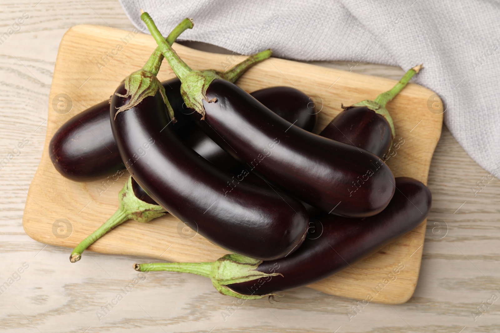 Photo of Many ripe eggplants on light wooden table, top view