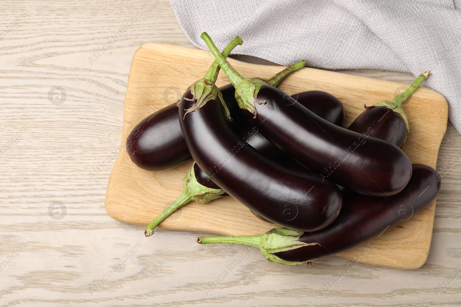Photo of Many ripe eggplants on light wooden table, top view