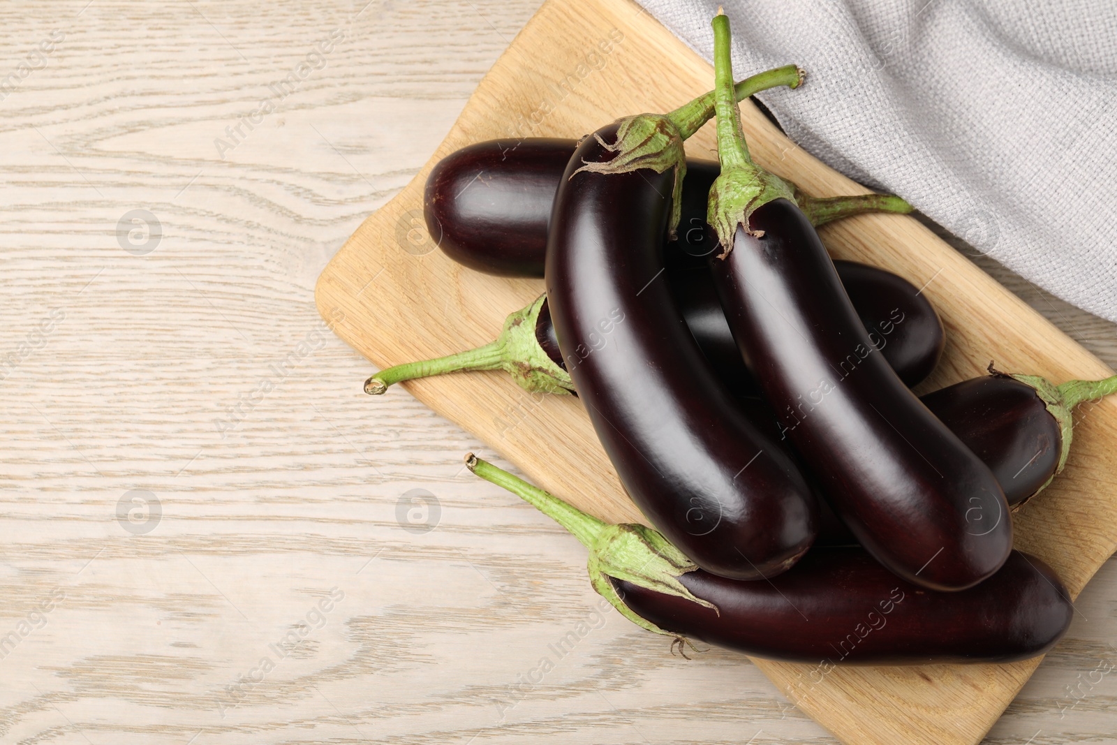 Photo of Many ripe eggplants on light wooden table, top view. Space for text