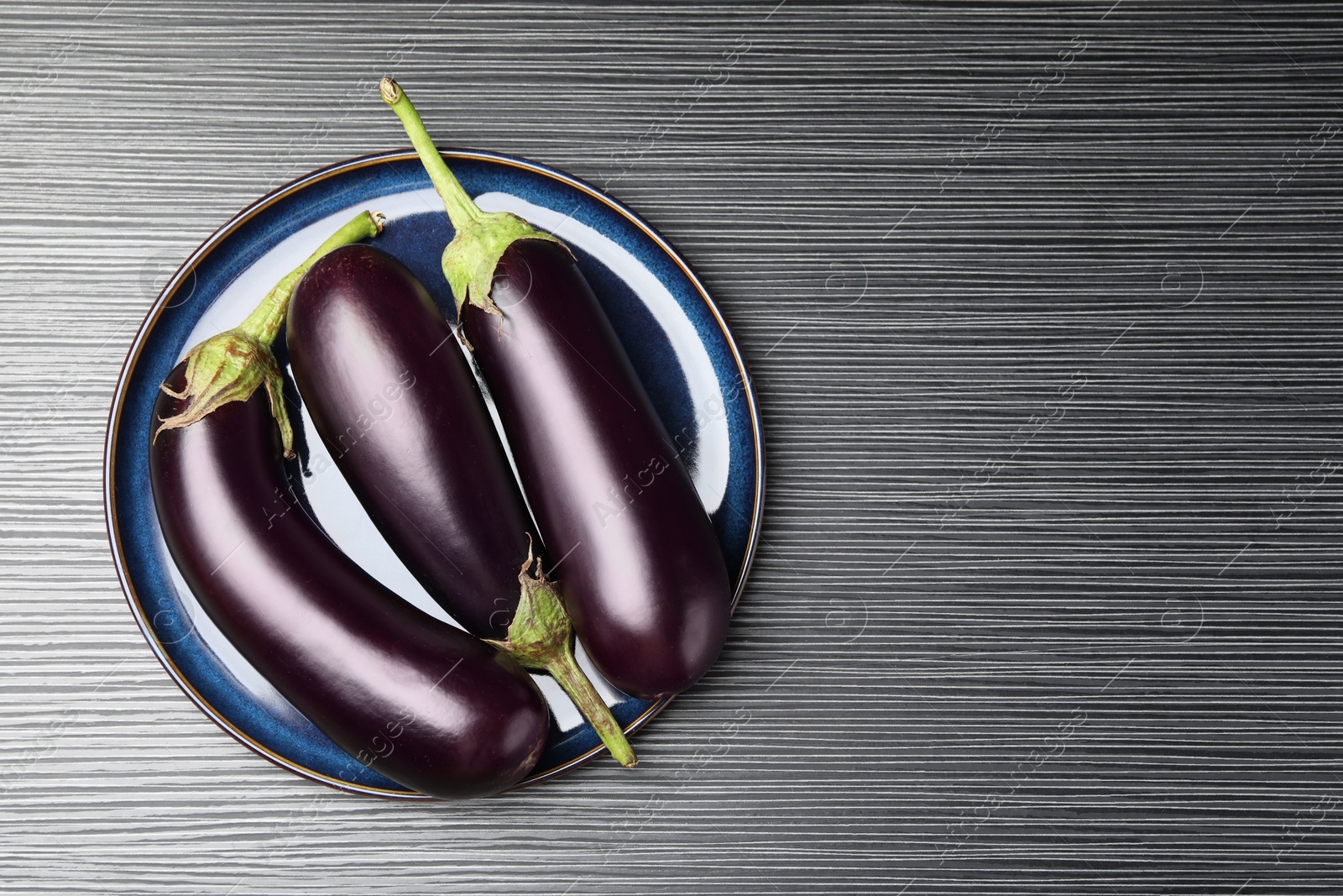 Photo of Many ripe eggplants on black wooden table, top view. Space for text