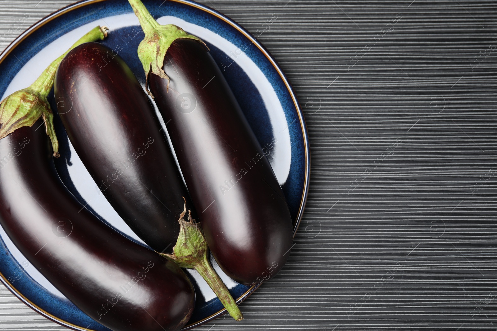 Photo of Many ripe eggplants on black wooden table, top view. Space for text