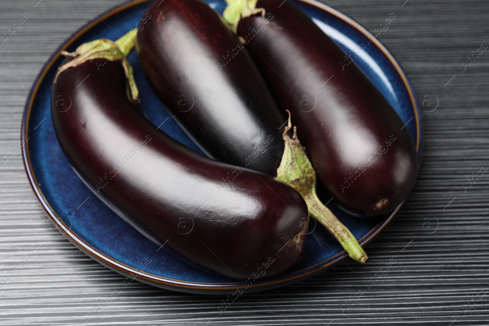 Photo of Many ripe eggplants on black wooden table, closeup