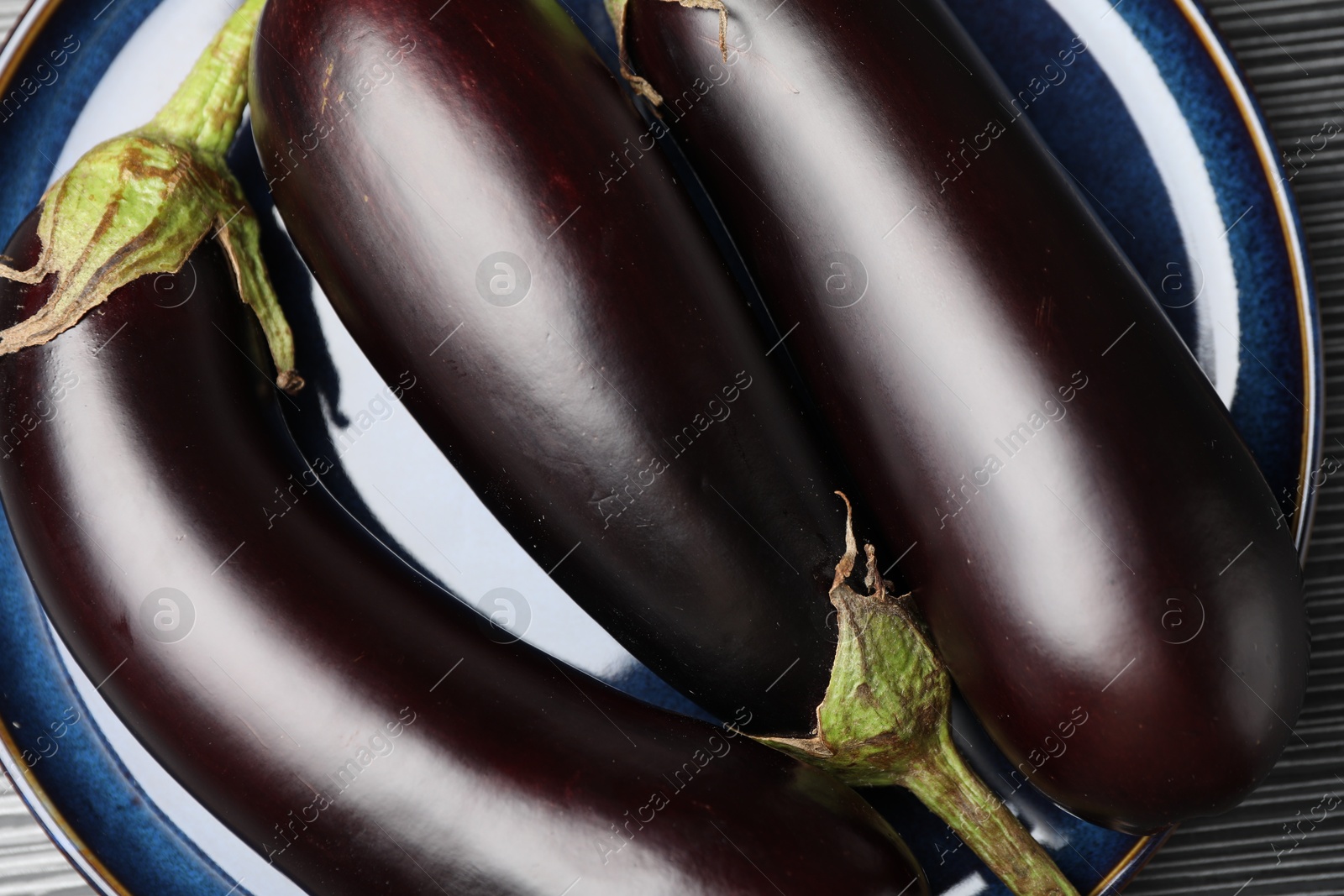 Photo of Many ripe eggplants on black wooden table, closeup