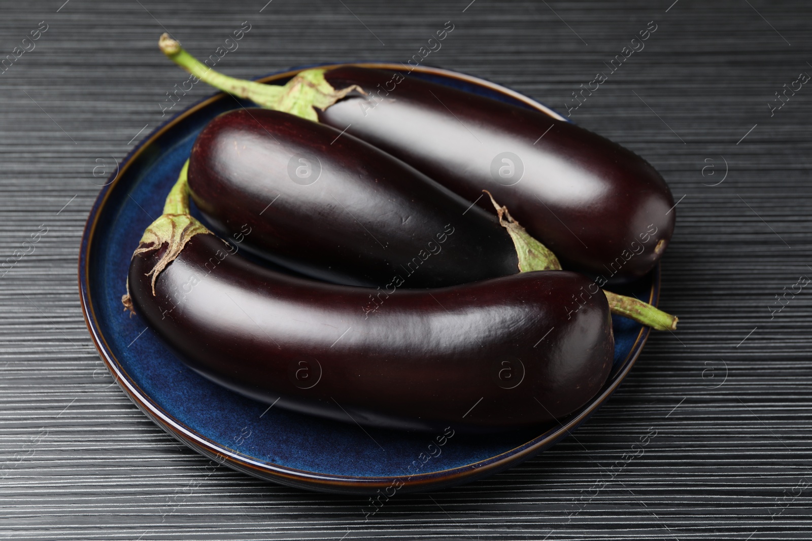 Photo of Many ripe eggplants on black wooden table, closeup
