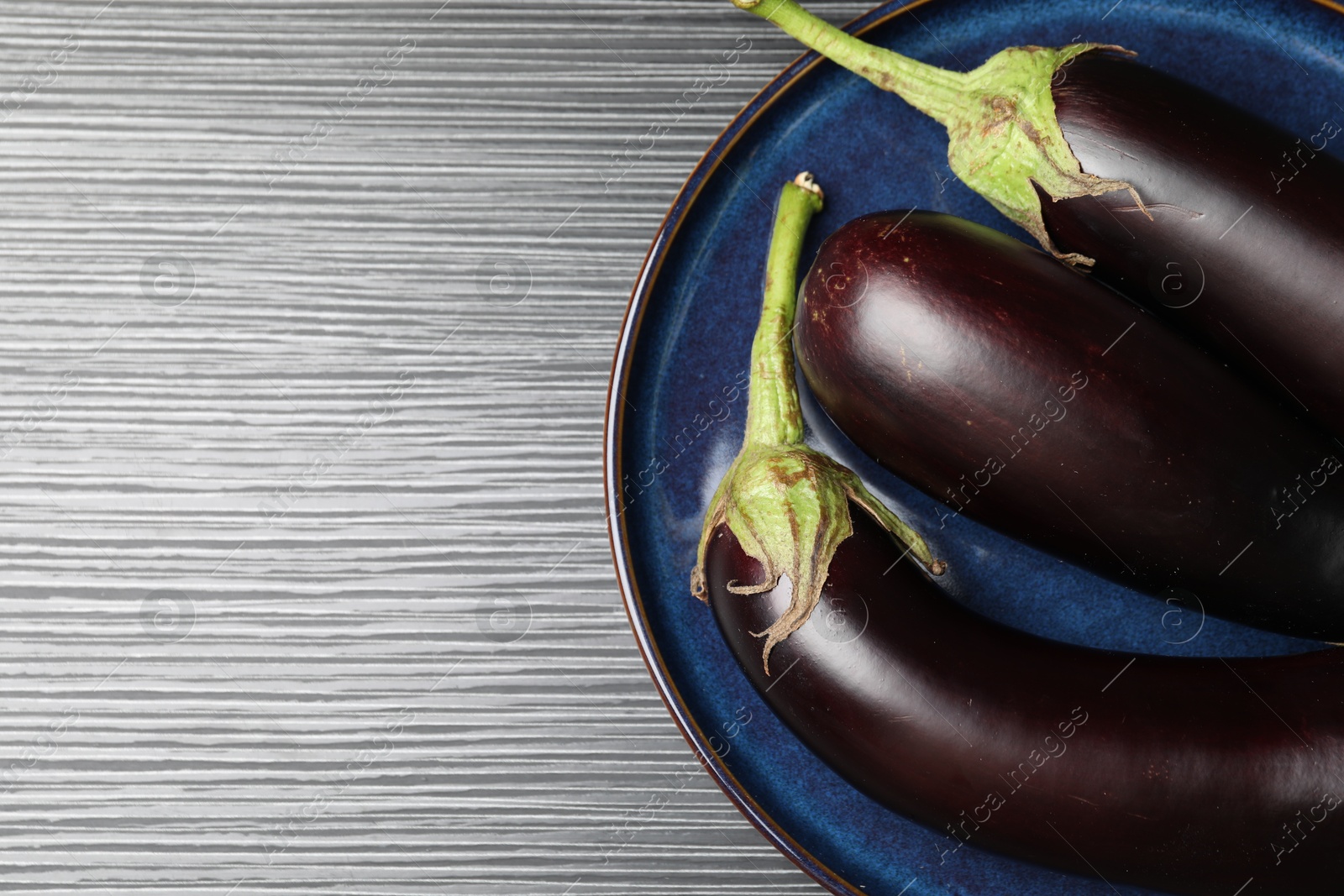 Photo of Many ripe eggplants on black wooden table, top view. Space for text