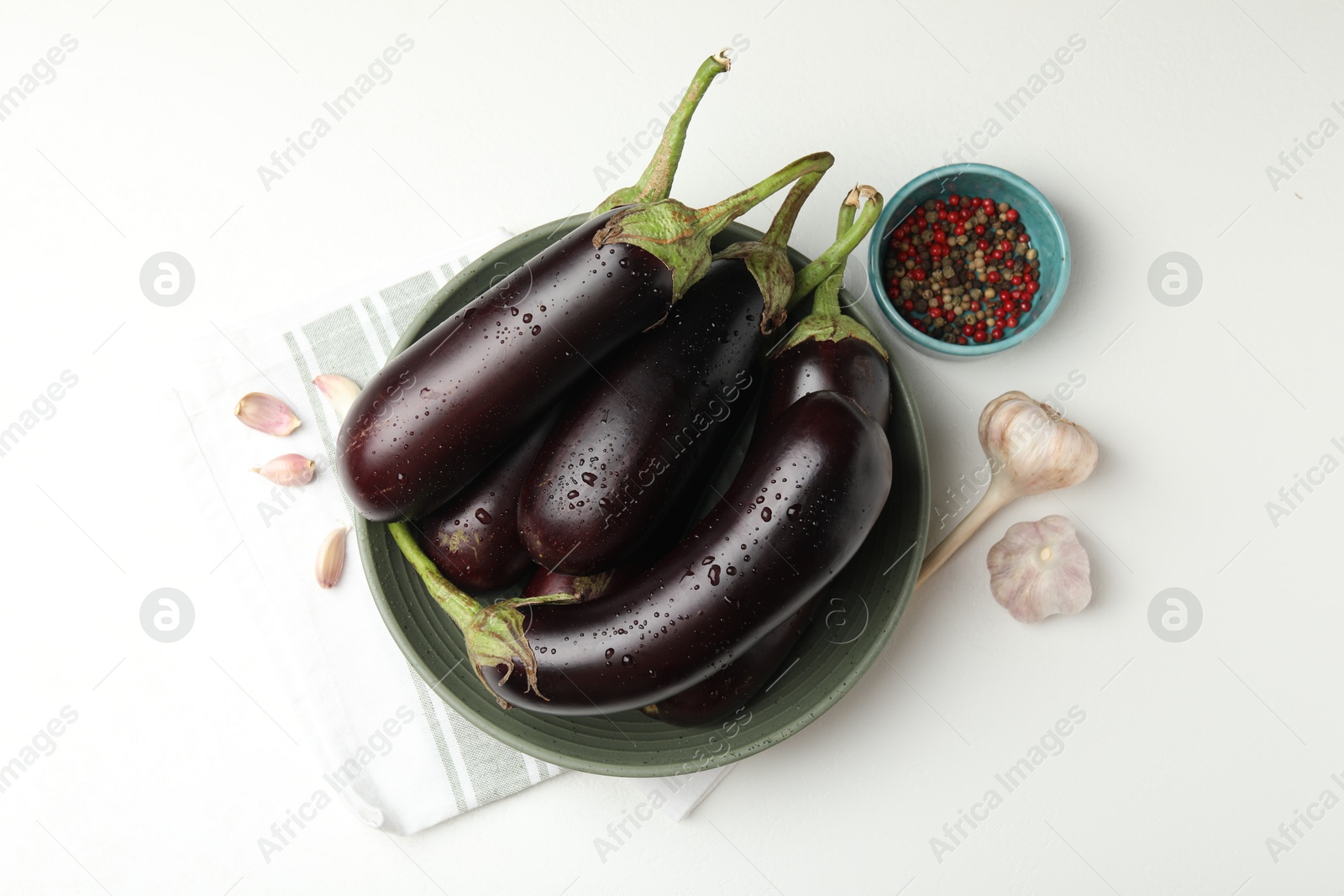 Photo of Many wet ripe eggplants, peppercorns and garlic on white table, flat lay