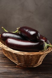 Photo of Many ripe eggplants in basket on wooden table