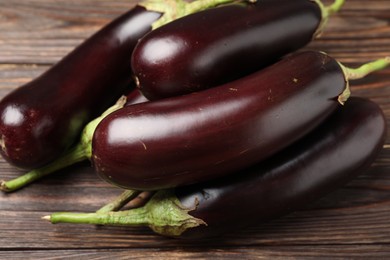 Photo of Many ripe eggplants on wooden table, closeup