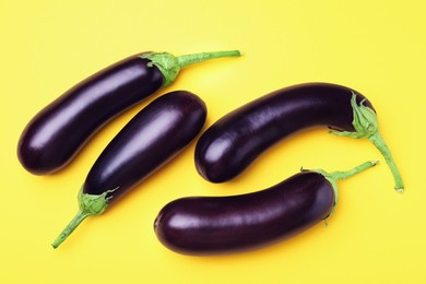 Photo of Ripe eggplants on yellow background, flat lay
