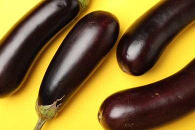 Photo of Ripe eggplants on yellow background, flat lay