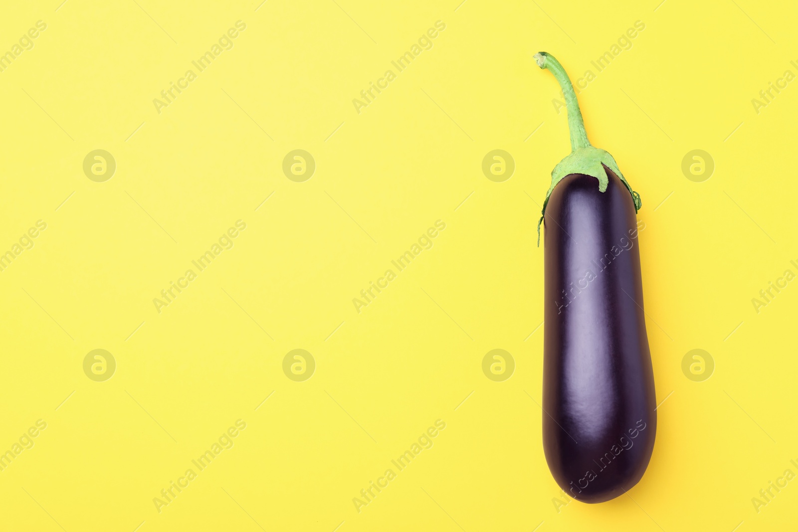 Photo of Ripe eggplant on yellow background, top view. Space for text