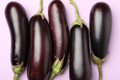 Photo of Ripe eggplants on light pink background, flat lay