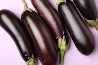 Photo of Ripe eggplants on light pink background, flat lay