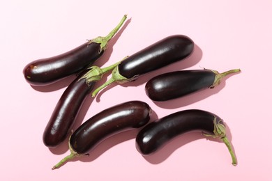 Photo of Ripe eggplants on light pink background, flat lay