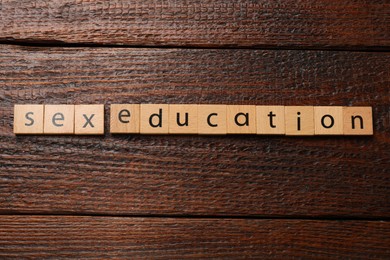 Photo of Phrase Sex Education made with wooden letters on table, top view