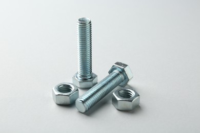 Photo of Metal bolts and nuts on white background, closeup. Hardware tool