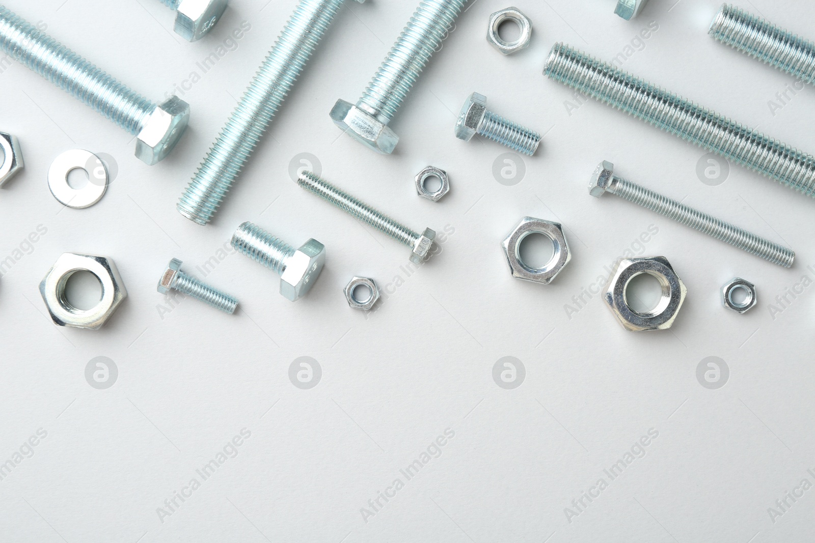Metal bolts and nuts on white background, flat lay. Space for text Photo of Metal bolts and nuts on white background, flat lay. Space for text