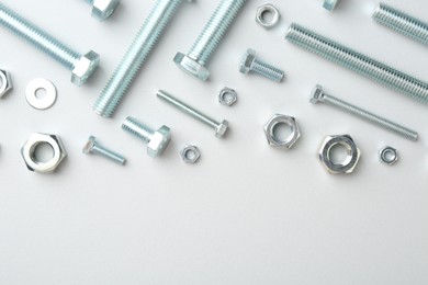 Photo of Metal bolts and nuts on white background, flat lay. Space for text
