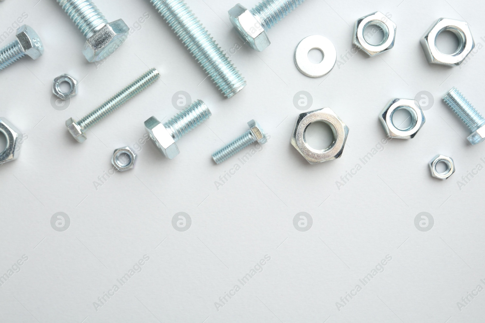 Metal bolts and nuts on white background, flat lay. Space for text Photo of Metal bolts and nuts on white background, flat lay. Space for text