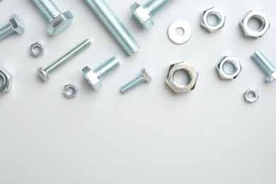 Photo of Metal bolts and nuts on white background, flat lay. Space for text