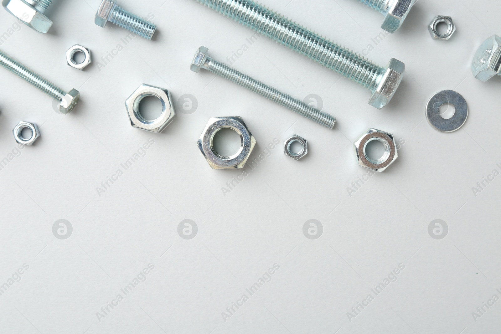 Metal bolts and nuts on white background, flat lay. Space for text Photo of Metal bolts and nuts on white background, flat lay. Space for text