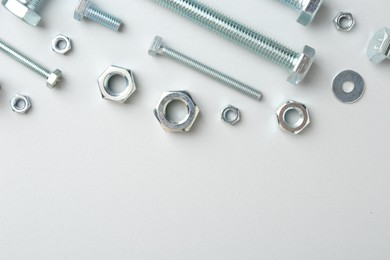 Photo of Metal bolts and nuts on white background, flat lay. Space for text