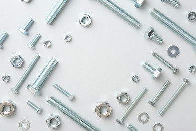 Photo of Metal bolts and nuts on white background, flat lay. Space for text