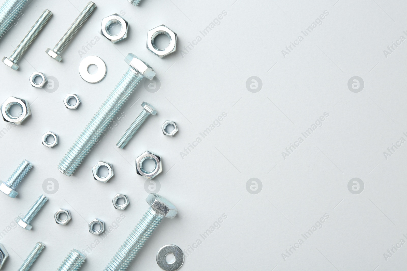 Metal bolts and nuts on white background, flat lay. Space for text Photo of Metal bolts and nuts on white background, flat lay. Space for text