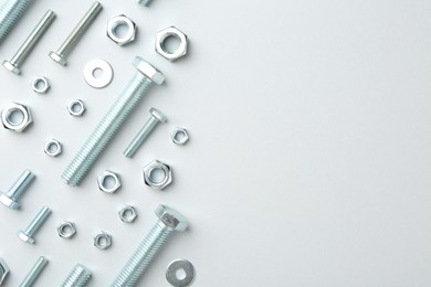 Photo of Metal bolts and nuts on white background, flat lay. Space for text