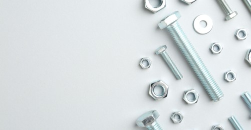 Photo of Metal bolts and nuts on white background, flat lay. Space for text