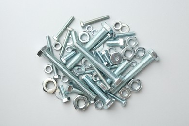 Photo of Metal bolts and nuts on white background, flat lay