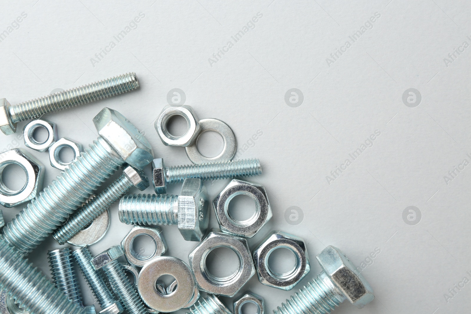Metal bolts and nuts on white background, flat lay. Space for text Photo of Metal bolts and nuts on white background, flat lay. Space for text