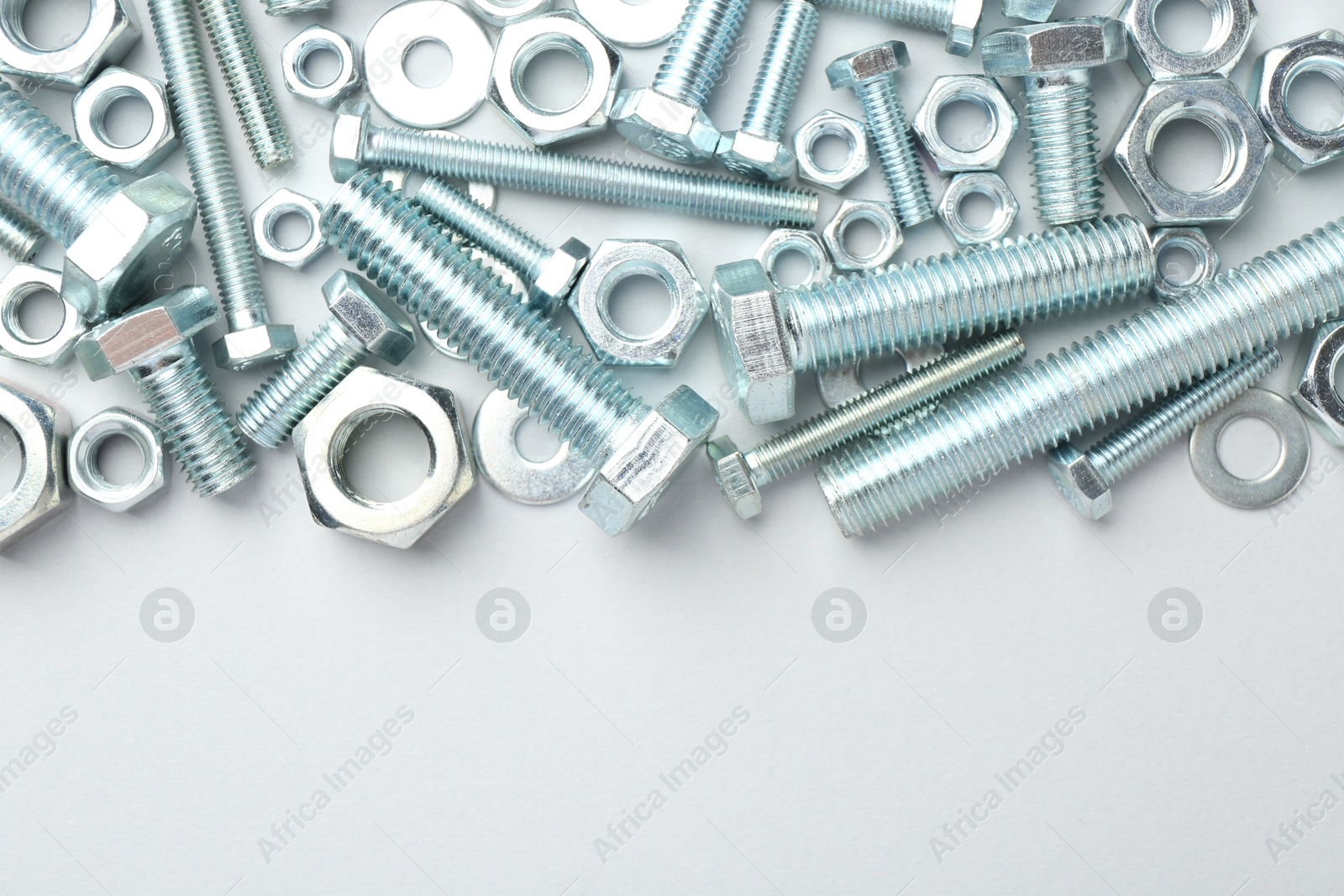 Metal bolts and nuts on white background, flat lay. Space for text Photo of Metal bolts and nuts on white background, flat lay. Space for text