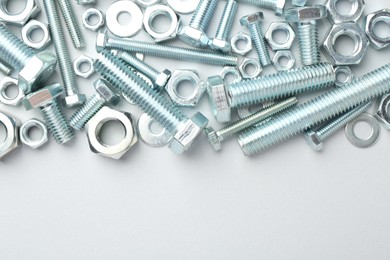 Photo of Metal bolts and nuts on white background, flat lay. Space for text