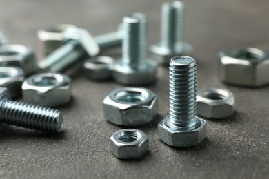 Photo of Metal bolts and nuts on grey table, closeup