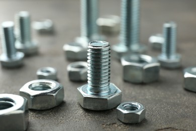 Photo of Metal bolts and nuts on grey table, closeup