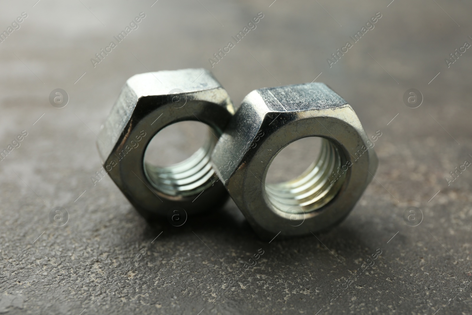 Metal hex nuts on grey table, closeup Photo of Metal hex nuts on grey table, closeup