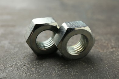Photo of Metal hex nuts on grey table, closeup