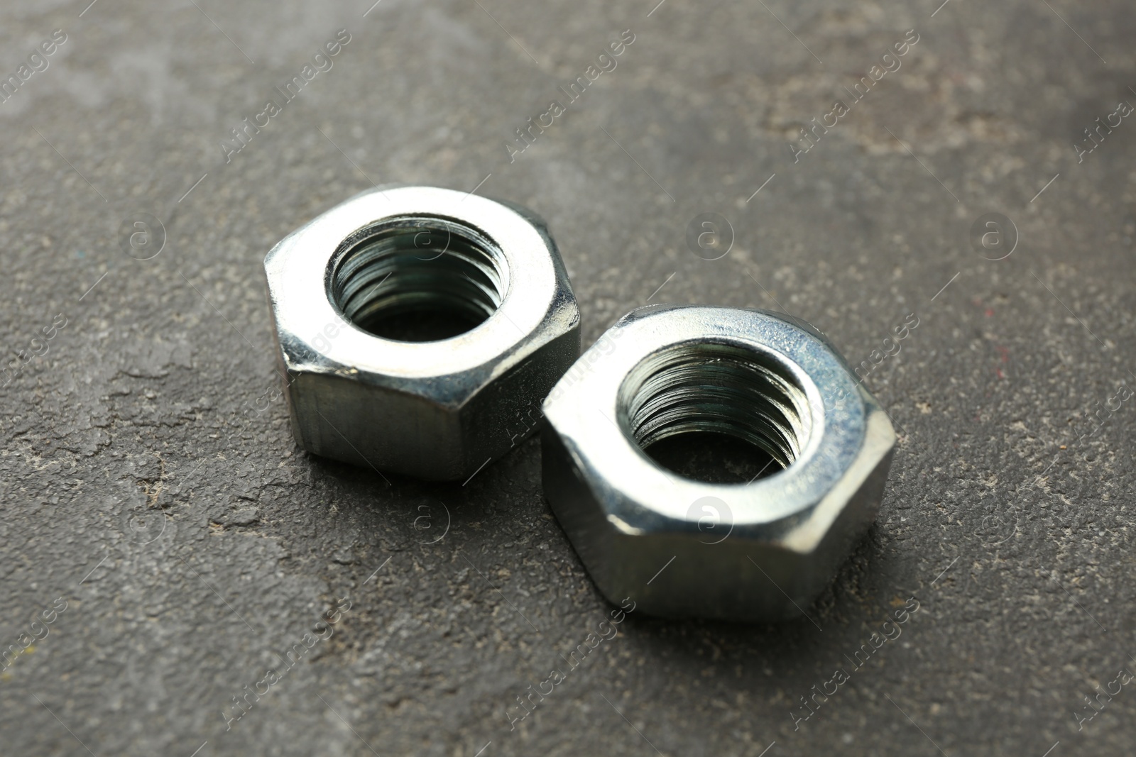 Metal hex nuts on grey table, closeup Photo of Metal hex nuts on grey table, closeup