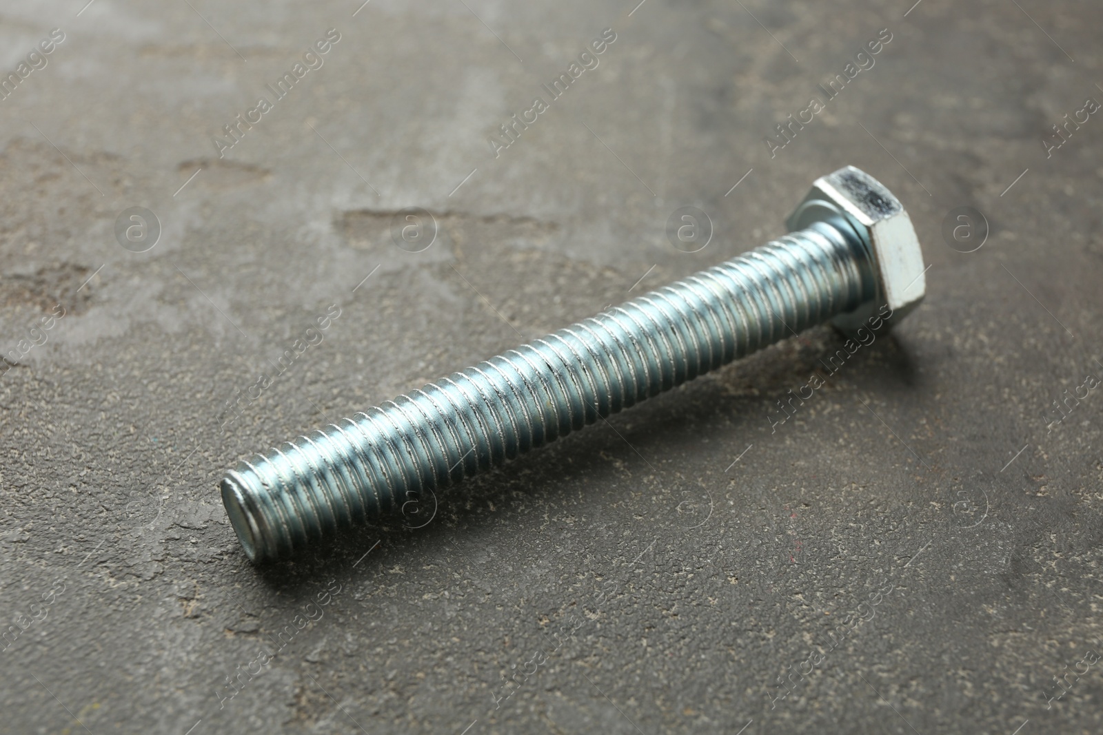 One metal bolt on grey table, closeup Photo of One metal bolt on grey table, closeup
