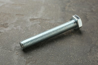 Photo of One metal bolt on grey table, closeup
