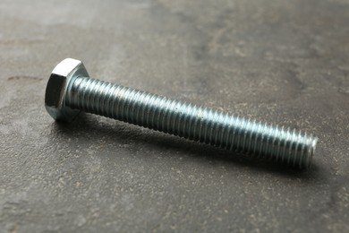 Photo of One metal bolt on grey table, closeup