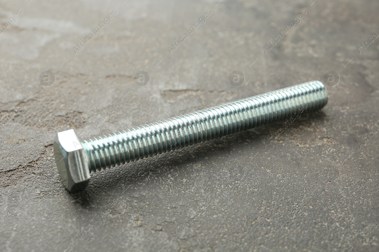 One metal bolt on grey table, closeup Photo of One metal bolt on grey table, closeup